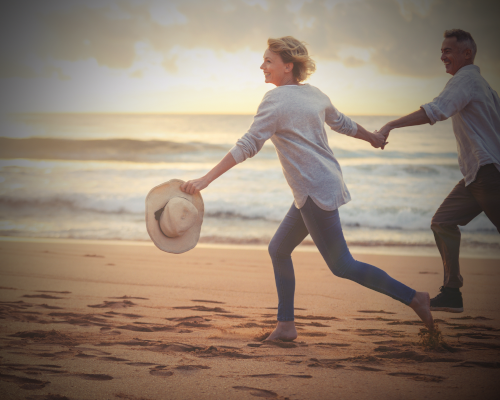 Mature couple running and playing on the beach at sunset or sunrise 500x400v